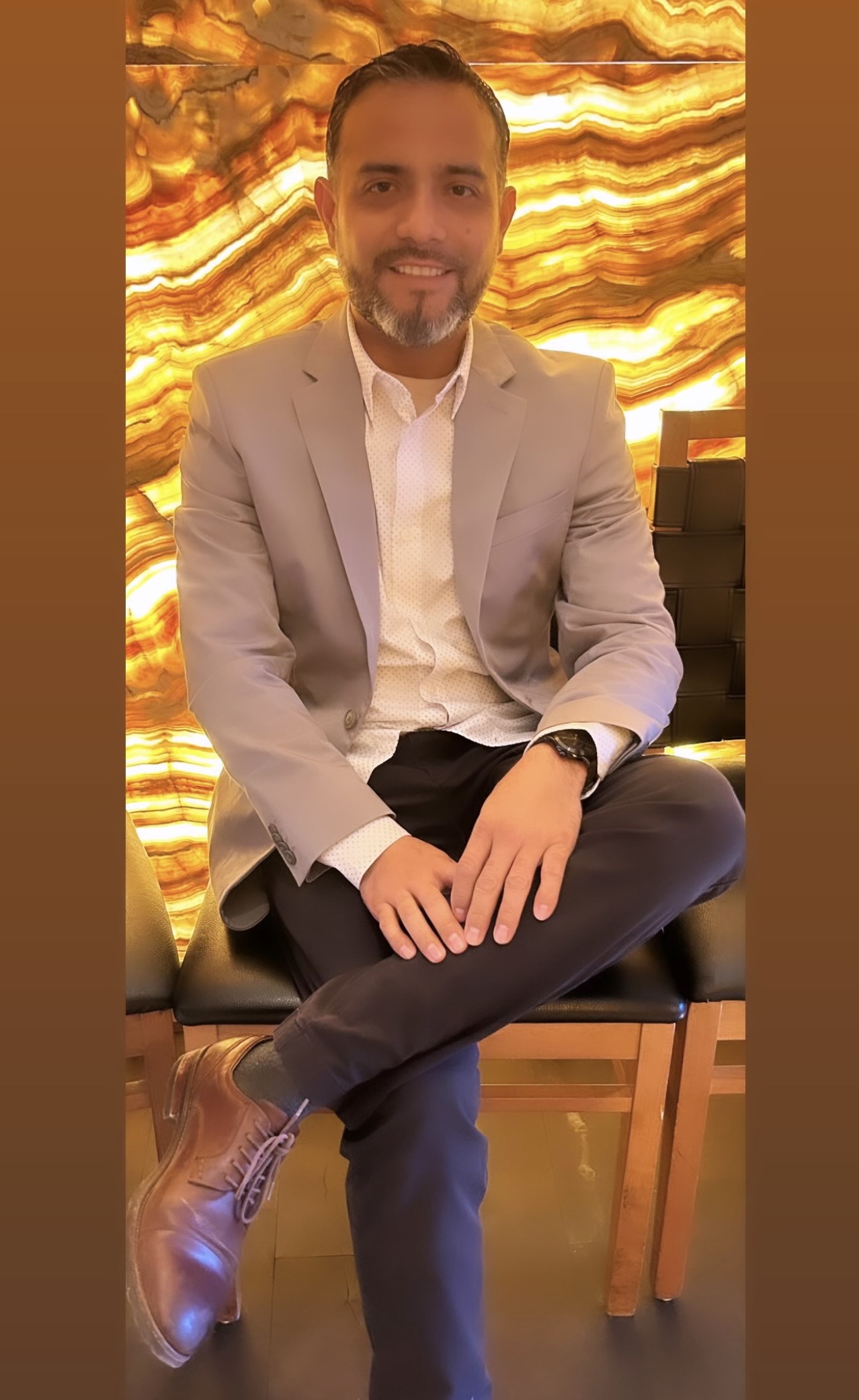 Photo of Angel, business owner sitting and smiling while facing the camera.